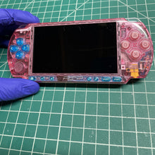 PSP in a clear pink shell, handled with gloves on a cutting mat