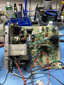 CRT monitor chassis on its metal frame, open on the repair bench in front of a rack of tools