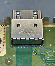 Metal HDMI connector seated on a green circuit board, close up
