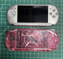 Silver PSP beside a clear pink replacement shell on a cutting mat