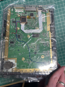 Console mainboard sealed in an antistatic bag on the bench